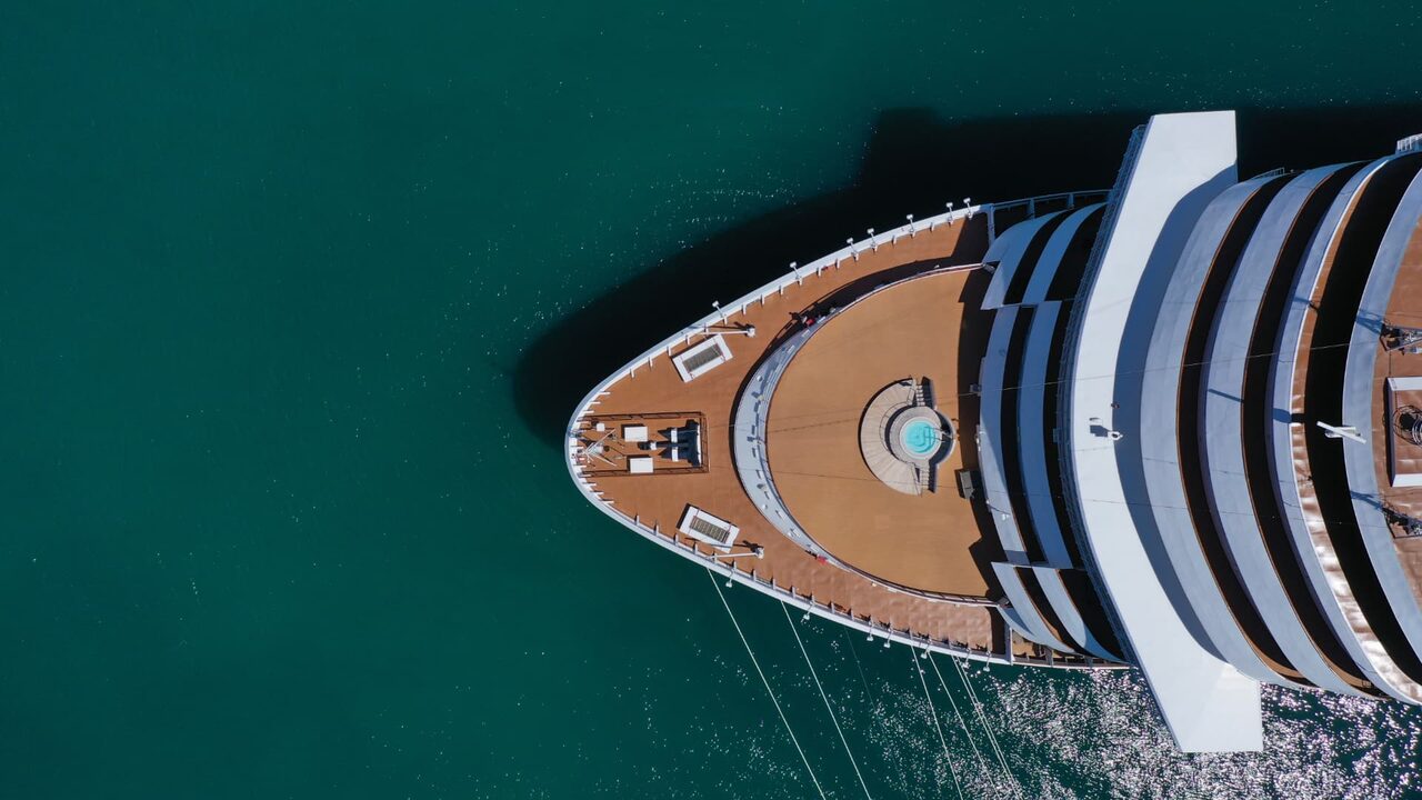 Aerial top-down view of a cruise ship bow moving through open water.
