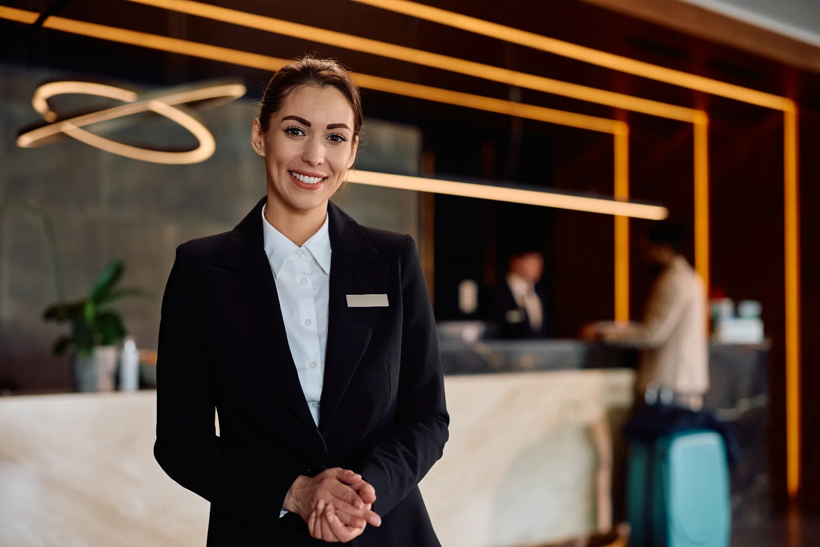 Smiling hotel front-desk manager in a modern lobby